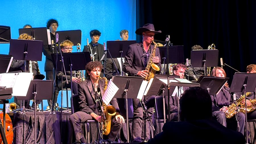 Davis standing to take a solo in a big band sax section on a blue-lit stage